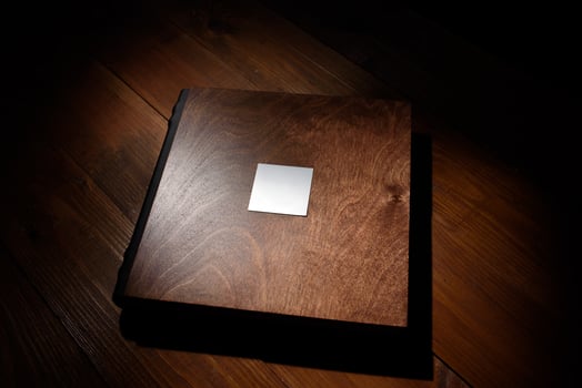 Photo book in a wooden cover on a wooden table. Hard light
