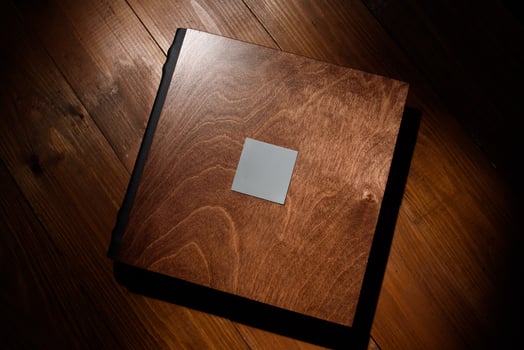 Photo book in a wooden cover on a wooden table. Hard light