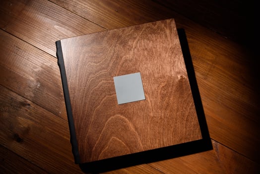 Photo book in a wooden cover on a wooden table. Hard light
