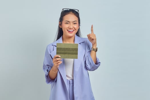 Portrait of cheerful young Asian woman pointing finger at empty space and holding vehicle book isolated on white background photo