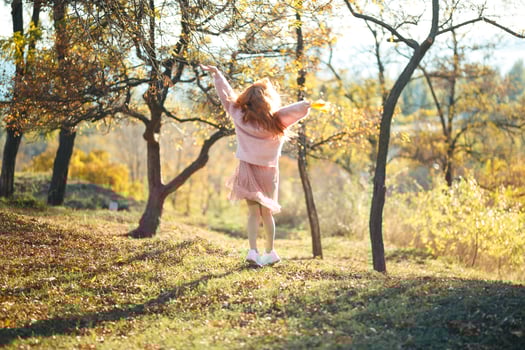 Portraits of a charming red-haired girl with a cute face. Girl posing in autumn park in a sweater and a coral-colored skirt. The girl has a wonderful mood photo