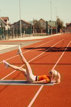 young blonde shakes abdominal muscles on a sports mat on the street photo