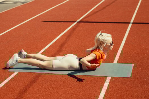young blonde shakes abdominal muscles on a sports mat on the street photo