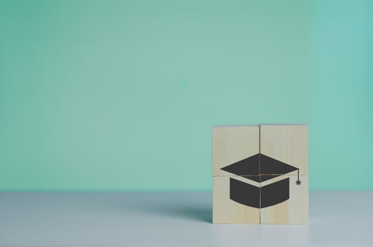Wooden cube with graduation cap icon.Education concept. Graduation day success on background copy space. photo