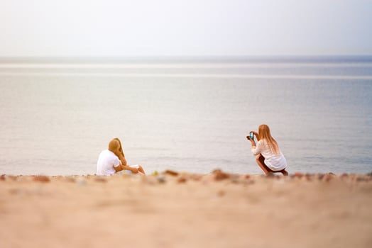 Photographer shooting loving couple in love on sandy beach, seascape horizon background outdoor photo