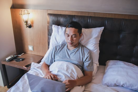 Serious man working on laptop while sitting on a bed photo