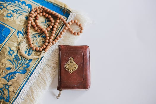 Top view of Holy Book Al Quran on the prayer mat and prayer beads with copy space. There is Arabic letter which means the holy book photo