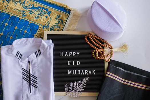 Top view of Muslim traditional dress and prayer beads on the prayer mat with letter board says Happy Eid Mubarak photo