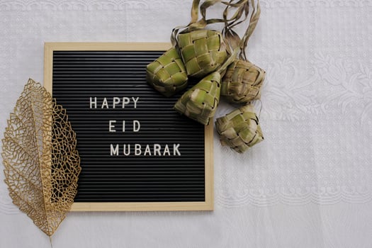 Top view of letter board says Happy Eid Mubarak and traditional food during lebaran celebration called ketupat with copy space photo
