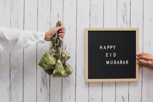 Hand holding rice cake in Indonesia called ketupat and letter board says Happy Eid Mubarak photo