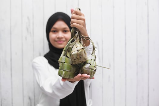 Asian Muslim Woman showing ketupat for Eid Mubarak celebration photo
