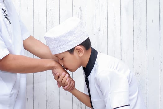 Muslim boy greeting and asking forgiveness by kissing hand at ramadan and eid mubarak photo