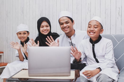 Happy Muslim family doing video conversation in front a laptop with say hi or greet gesture by hand on Eid Mubarak celebration photo