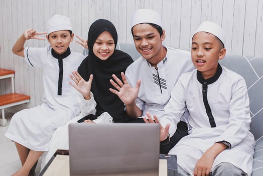 Happy Muslim family doing video conversation in front a laptop with say hi or greet gesture by hand on Eid Mubarak celebration photo
