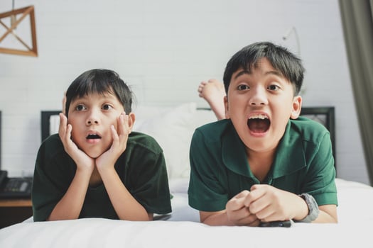 Two brother lying on the bed watching television with socked expression photo