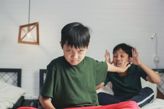 Abused boy by elder brother doing stop gesture using hand on the bed photo