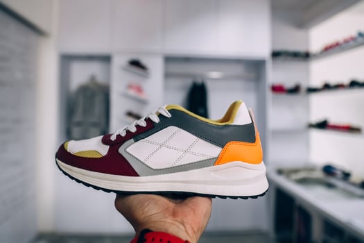 Hand holding sneaker with blurry background of fashion store photo