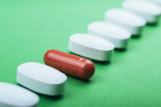Medical white pills and brown capsules for the treatment and health care on a green background photo