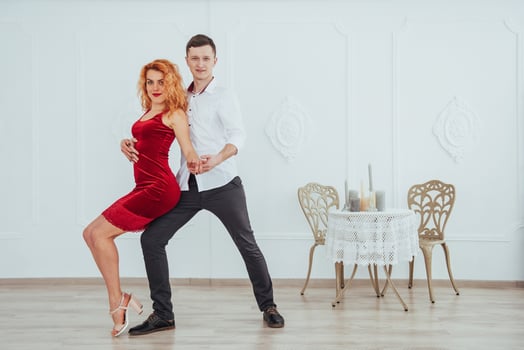 Young beautiful woman in a red dress and a man dancing, isolated on a white background. photo