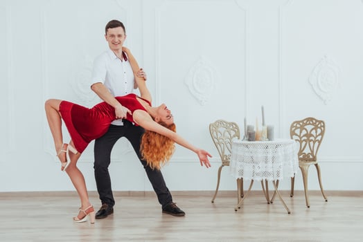 Young beautiful woman in a red dress and a man dancing, isolated on a white background. photo