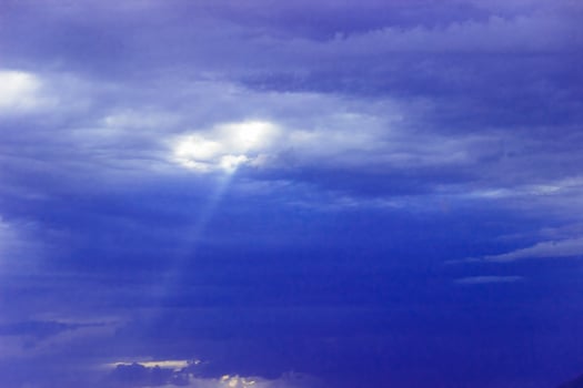 through the clouds over the sea a ray of sunshine makes its way photo