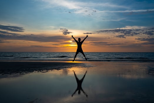Silhouette of man Jumping on Beach at Sunset photo