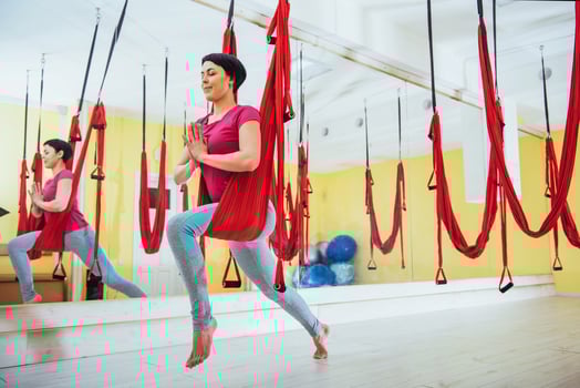 Young beautiful woman practicing yoga Fly with a hammock in the bright studio. Flying, fitness, stretch, balance, exercise. photo