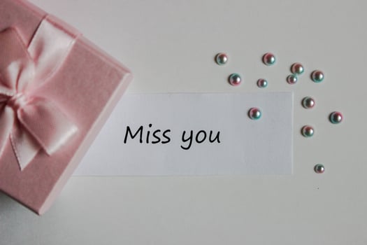 Note miss you with gift box and decorative pearls on white background photo