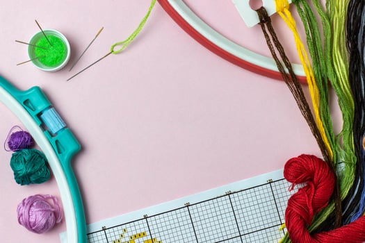 A cross-stitching items frame with copy space. Accessories for embroidery threads of moulin of different colors, needles, scheme, hoops, canvas. Hobbies, pastime, activity, art, handmade photo