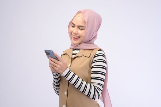 Portrait of beautiful woman with hijab using cellphone on white background photo