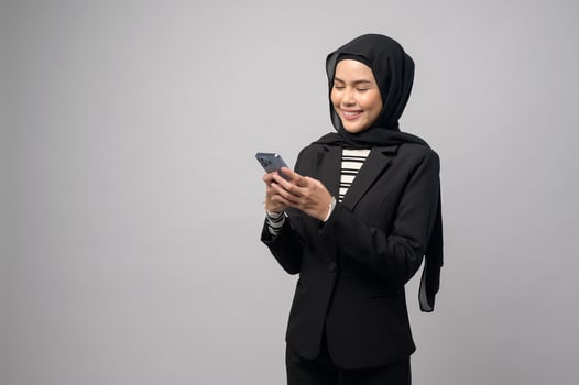 Portrait of beautiful woman with hijab using cellphone on white background photo