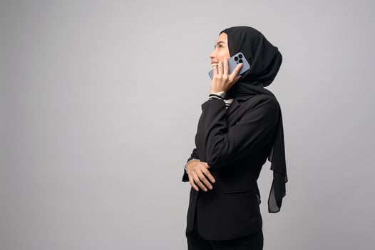 Portrait of beautiful woman with hijab using cellphone on white background photo