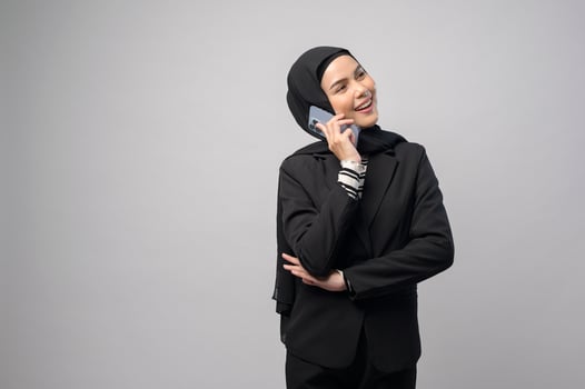 Portrait of beautiful woman with hijab using cellphone on white background photo