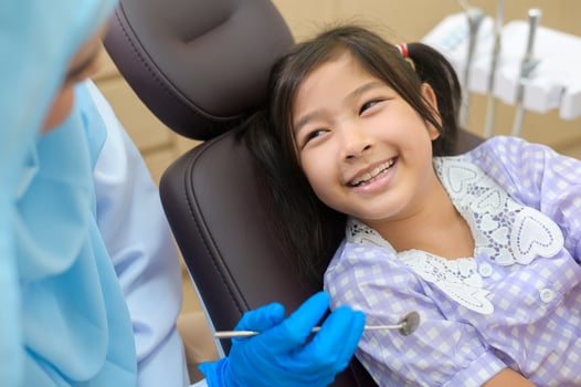 A little cute girl having teeth examined by muslim dentist in dental clinic, teeth check-up and Healthy teeth concept photo