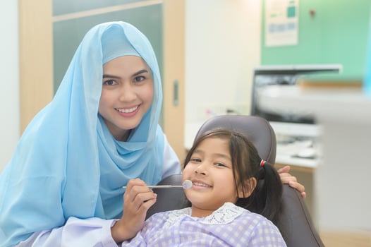 A little cute girl having teeth examined by muslim dentist in dental clinic, teeth check-up and Healthy teeth concept photo