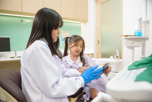 Female dentist explaining teeth x-ray to a little girl in dental clinic, teeth check-up and Healthy teeth concept photo