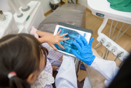 Female dentist explaining teeth x-ray to a little girl in dental clinic, teeth check-up and Healthy teeth concept photo