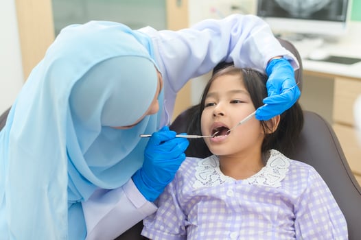 A little cute girl having teeth examined by muslim dentist in dental clinic, teeth check-up and Healthy teeth concept photo