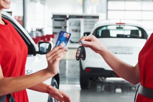 auto business, car sale, deal, gesture and people concept - close up of dealer giving key to new owner in auto show or salon photo