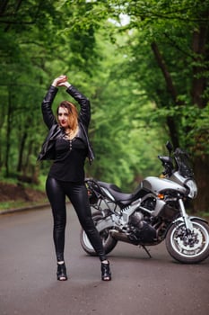 An attractive sexy girl on a sports motorbike posing outside photo