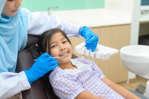 A little cute girl having teeth examined by muslim dentist in dental clinic, teeth check-up and Healthy teeth concept photo