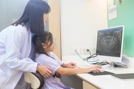Female dentist explaining teeth x-ray to a little girl in dental clinic, teeth check-up and Healthy teeth concept photo