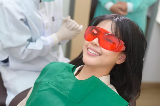 A woman wearing protective glasses  examining by stomatologist , Tooth whitening by ultraviolet lamp photo