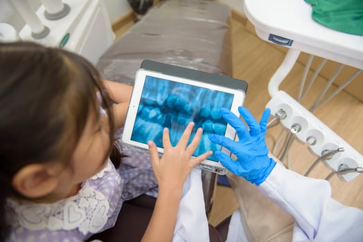 Female dentist explaining teeth x-ray to a little girl in dental clinic, teeth check-up and Healthy teeth concept photo