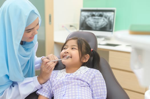 A little cute girl having teeth examined by muslim dentist in dental clinic, teeth check-up and Healthy teeth concept photo