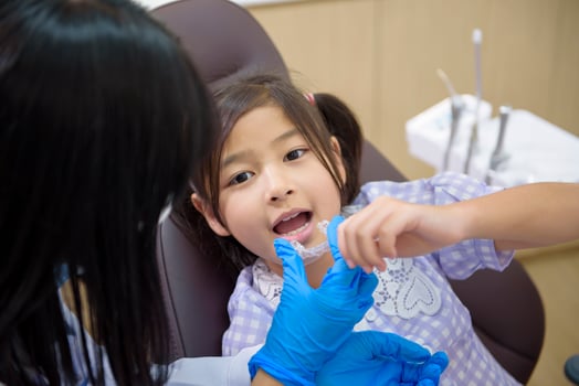 Female dentist showing invisalign to a little girl in dental clinic, teeth check-up and Healthy teeth concept photo