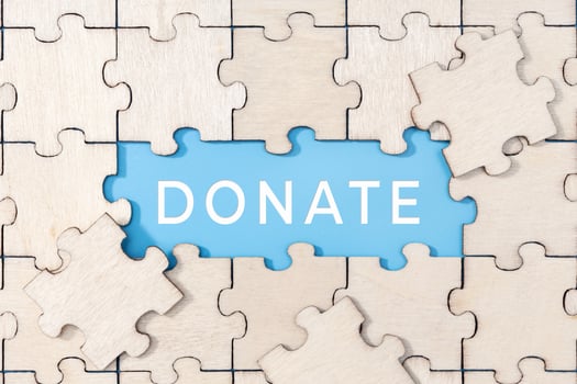 Donate word on blue background surrounded by puzzle pieces photo