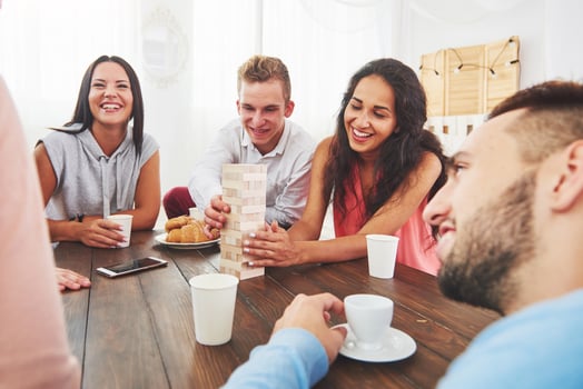 Group of creative friends sitting at wooden table. People having fun while playing board game photo