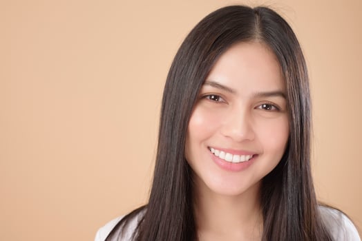 A Portrait of Asian woman with white T-shirt over Light brown background studio photo