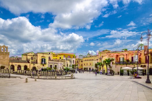 people tourists walking down Piazza Vittorio Veneto square with stone buildings in Matera old town historical centre photo
